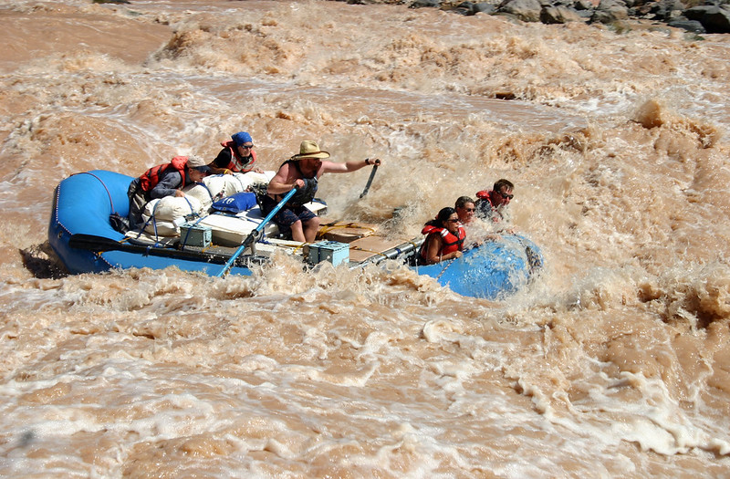 a large blue raft on a muddy, red brown frothy water.